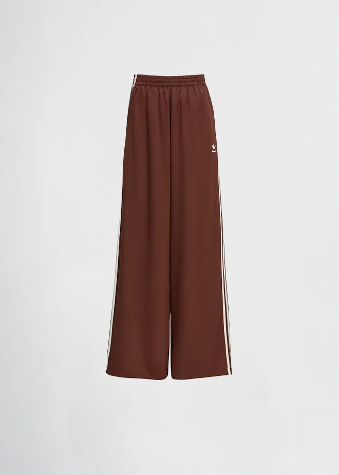 Woman wearing a cream-colored Adidas tracksuit on a light gray background